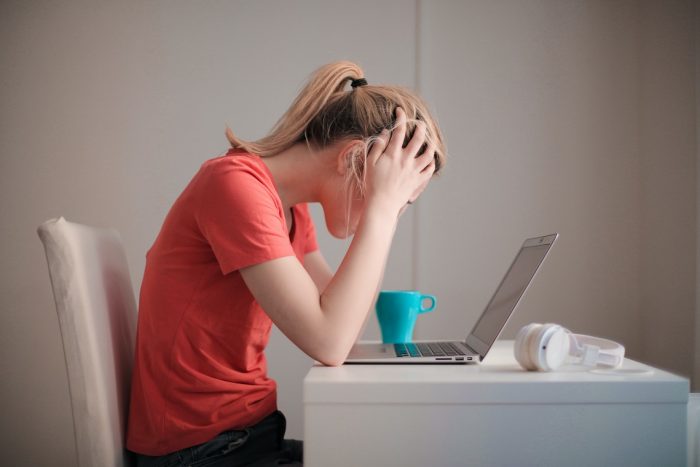 Jeune femme qui regarde son ordinateur en se prenant la tête, l'air impuissant