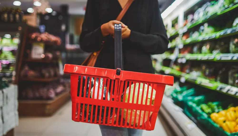 Une étudiante tient un panier d'épicerie 